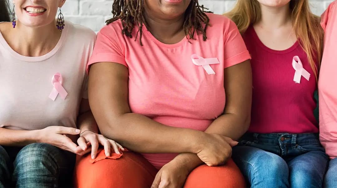 three women on couch with breast cancer awareness pins